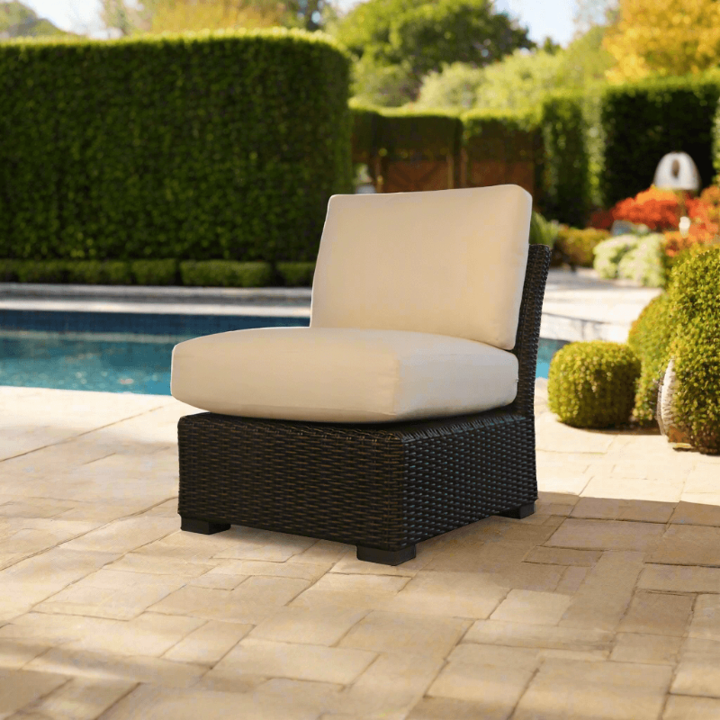 Patio chair with beige cushion on a paved area near a pool
