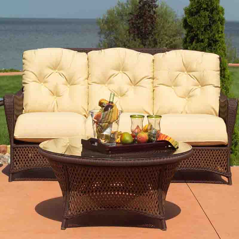 Outdoor patio set with beige cushions and a round table by a body of water.