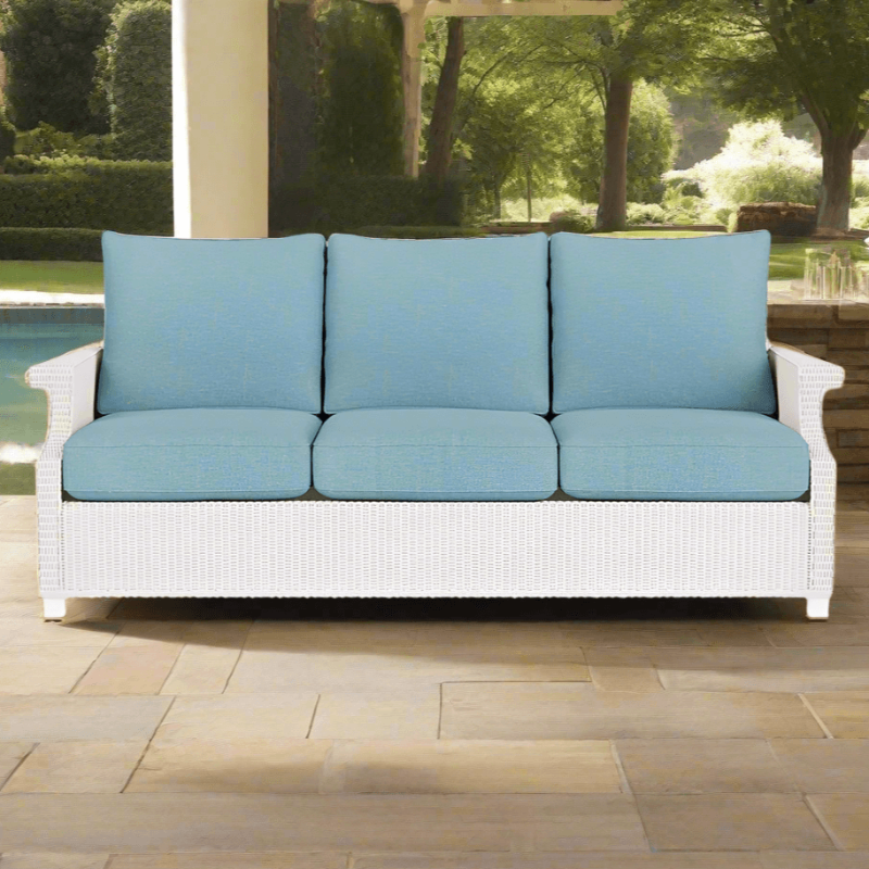 White wicker outdoor sofa with blue cushions on a patio