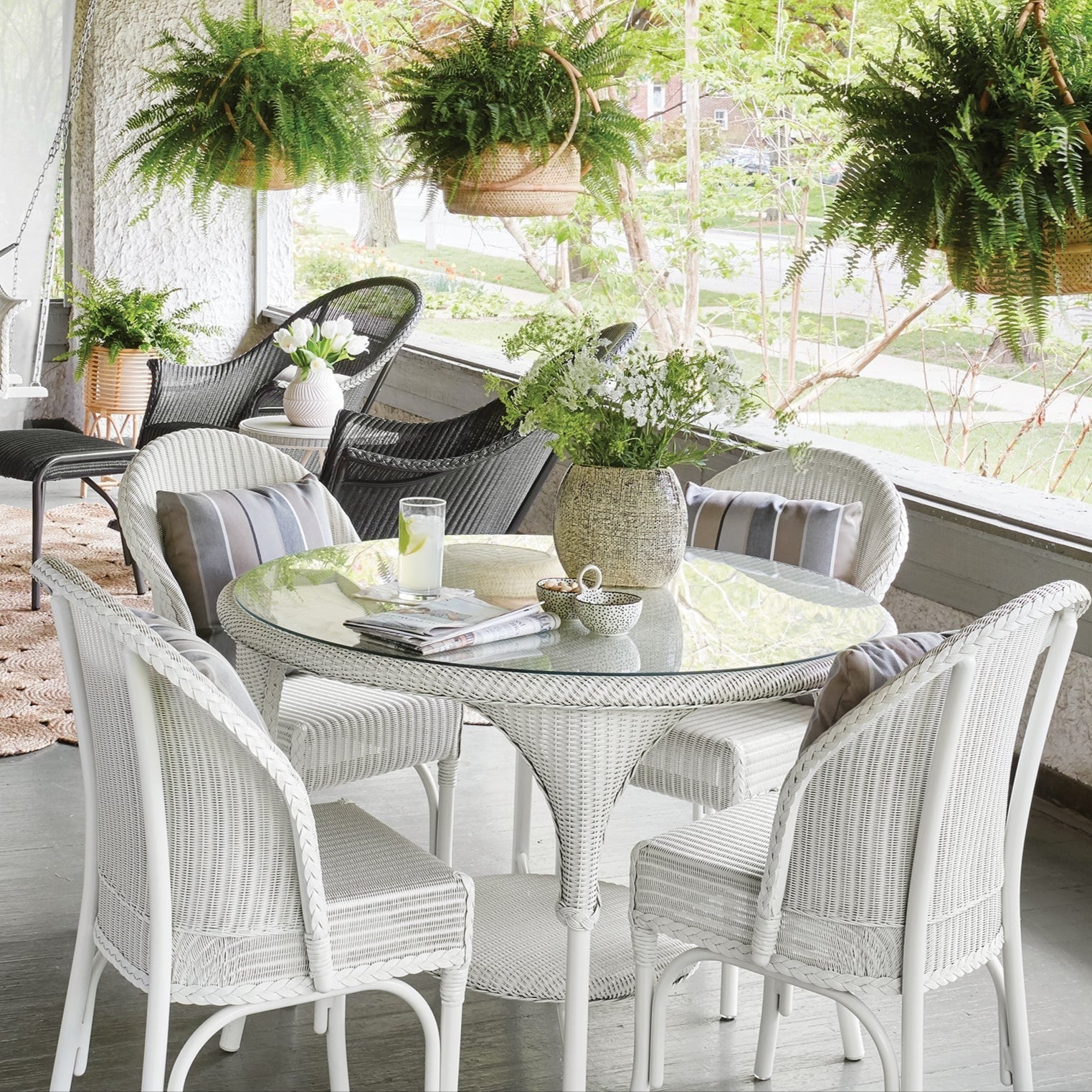 Outdoor patio with white furniture, plants, and a rug.