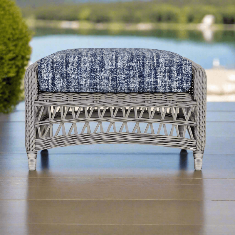 Wicker bench with a blue cushion on a wooden deck by a body of water.