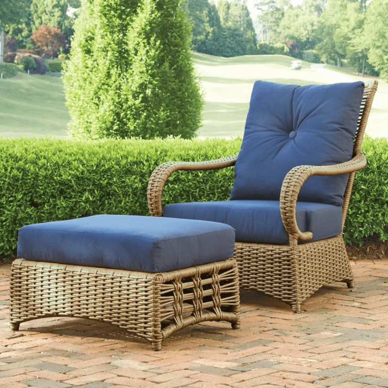 Wicker outdoor chair and ottoman with blue cushions on a patio