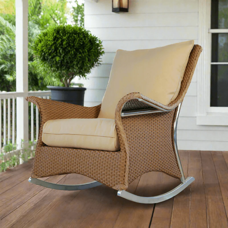 Wicker rocking chair with beige cushions on a wooden deck