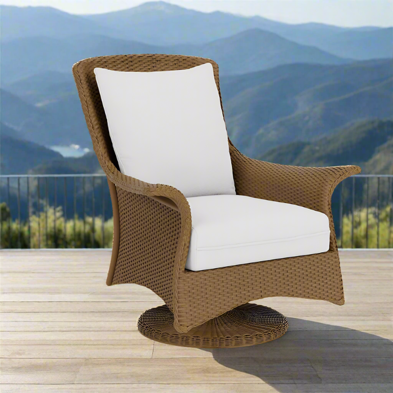 Wicker chair with white cushion on a wooden deck with mountainous landscape in the background