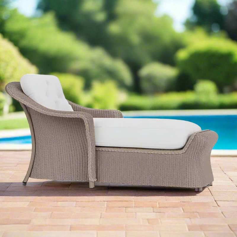 Wicker outdoor lounge chair with white cushions by a poolside