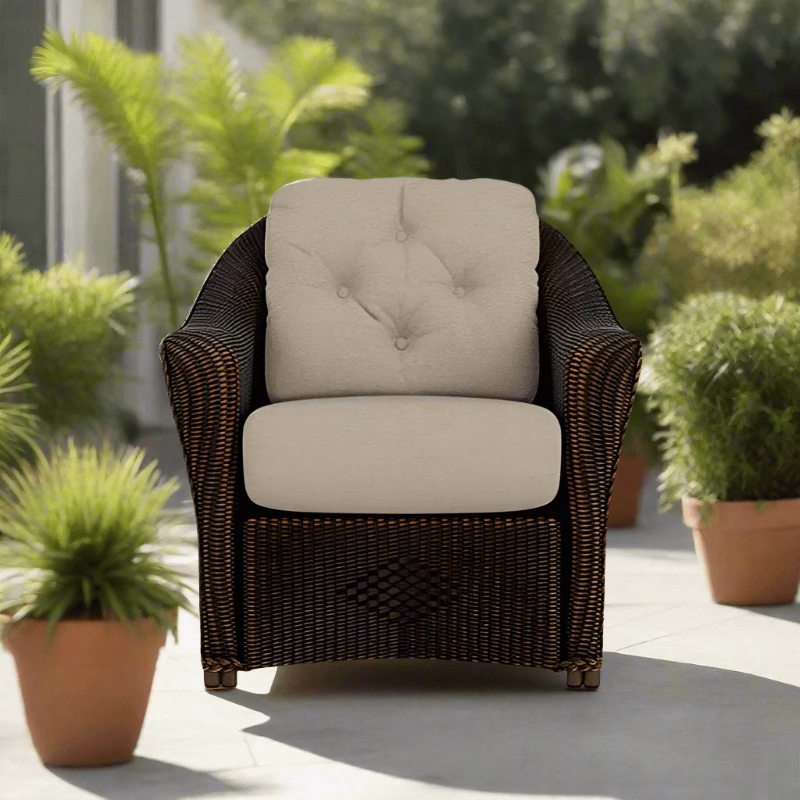 Wicker chair with beige cushions on a patio surrounded by potted plants