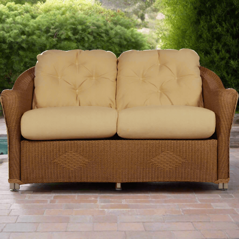 Wicker outdoor sofa with beige cushions on a patio