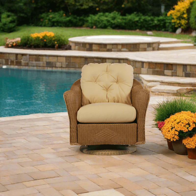Wicker chair with beige cushions on a patio by a pool