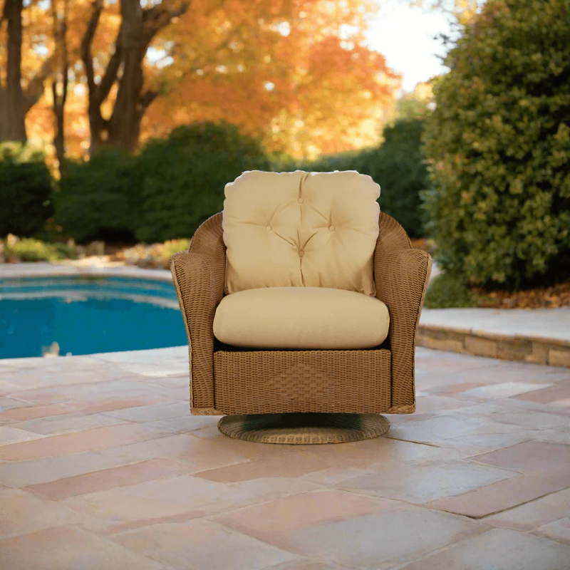 Wicker chair with beige cushions on a patio near a pool