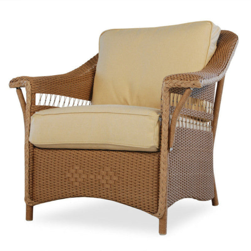 A beige wicker lounge chair with a plush cushion backrest and seat, featuring a classic weave pattern.