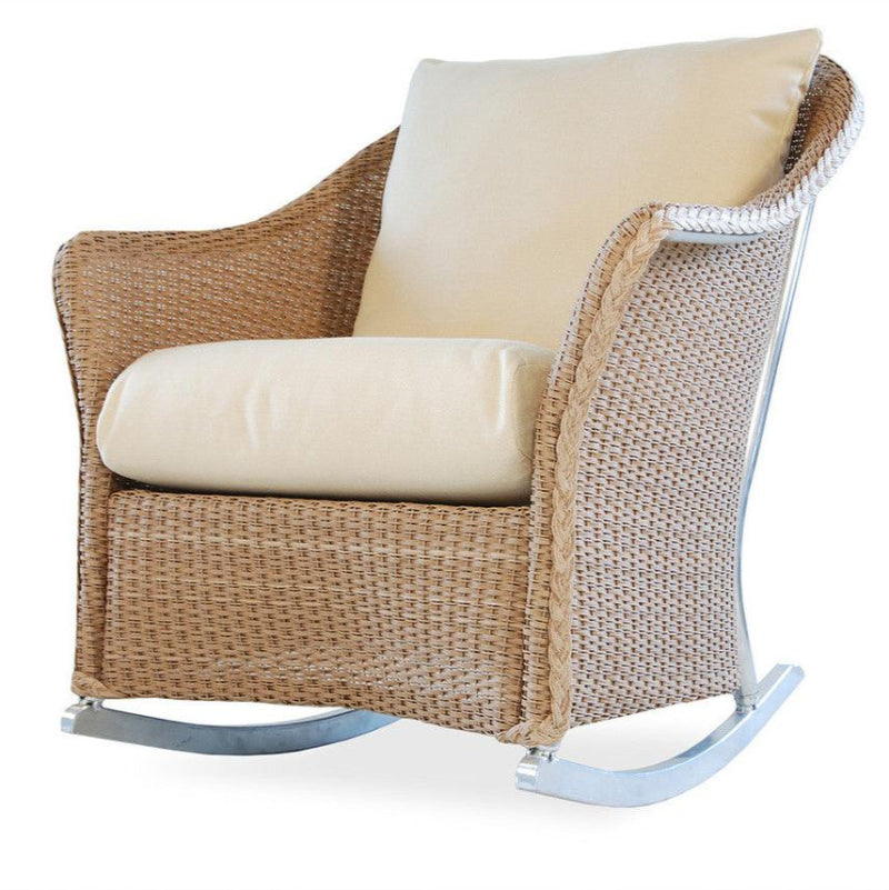 A beige wicker lounge rocker with a cushioned seat and backrest, featuring a classic curved design and a visible welded aluminum frame.