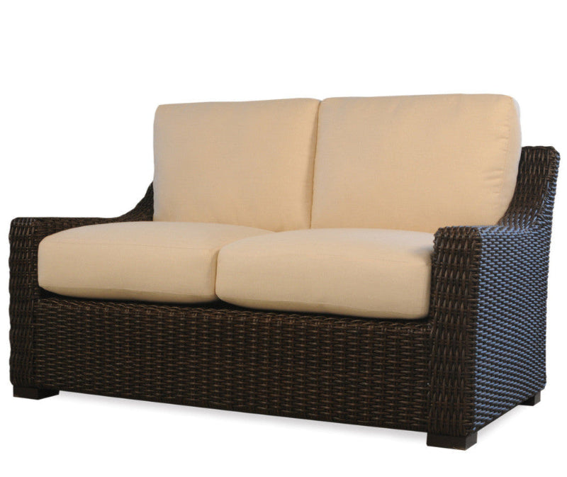 Wicker loveseat with beige cushions on a white background