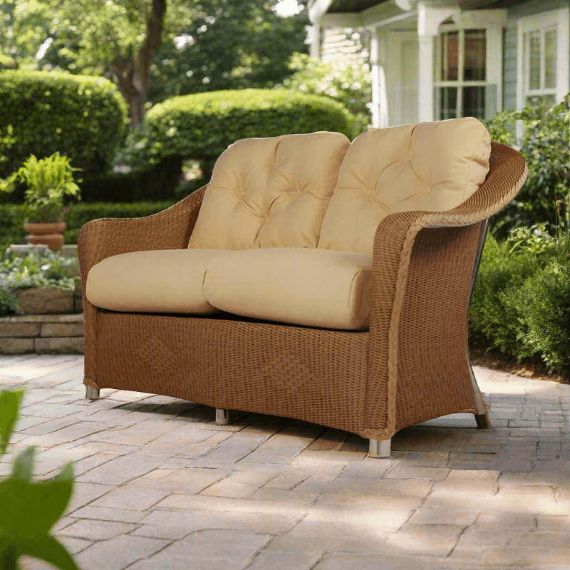 Wicker loveseat with beige cushions on a patio