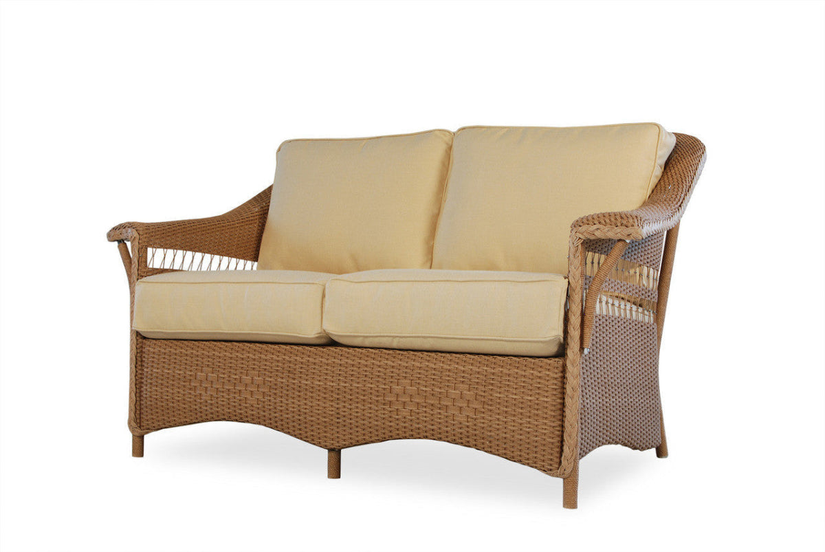 Wicker loveseat with beige cushions on a white background