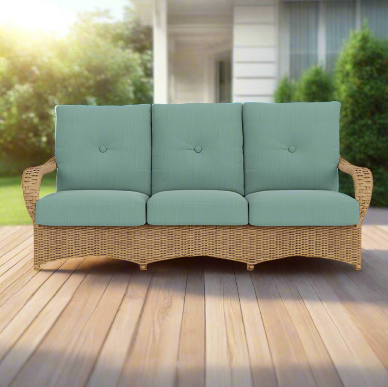 Wicker outdoor sofa with teal cushions on a wooden deck