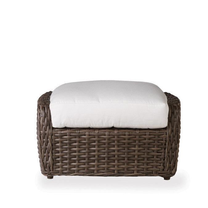 Wicker ottoman with a white cushion on a white background