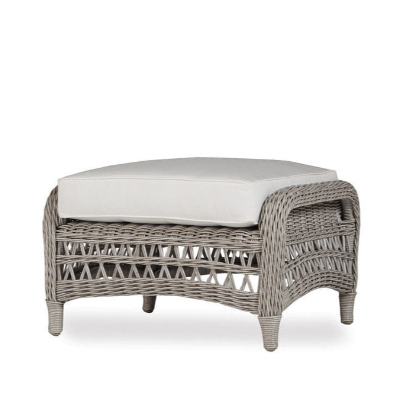 Wicker ottoman with a white cushion on a white background