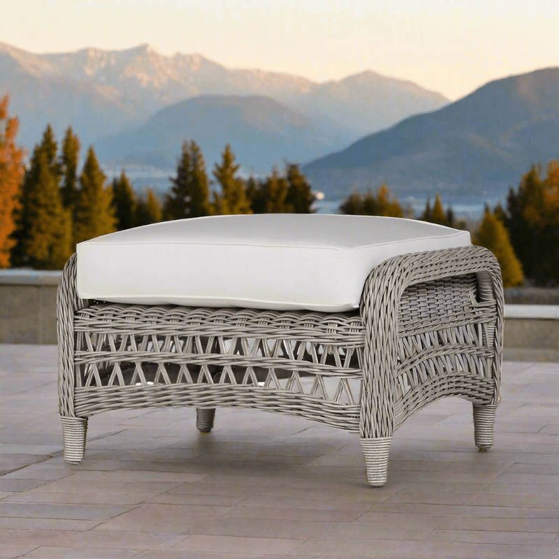 Wicker outdoor ottoman with white cushion on a patio with mountain view