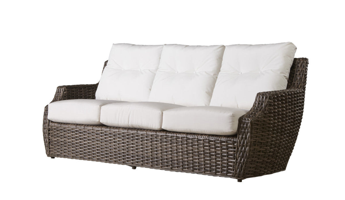 An outdoor woven vinyl sofa with a durable, textured weave, featuring a white cushioned seat and backrest, with a brown wicker frame.