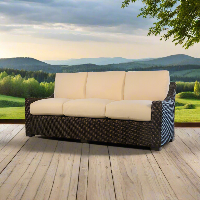 Outdoor sofa with beige cushions on a wooden deck with a scenic background