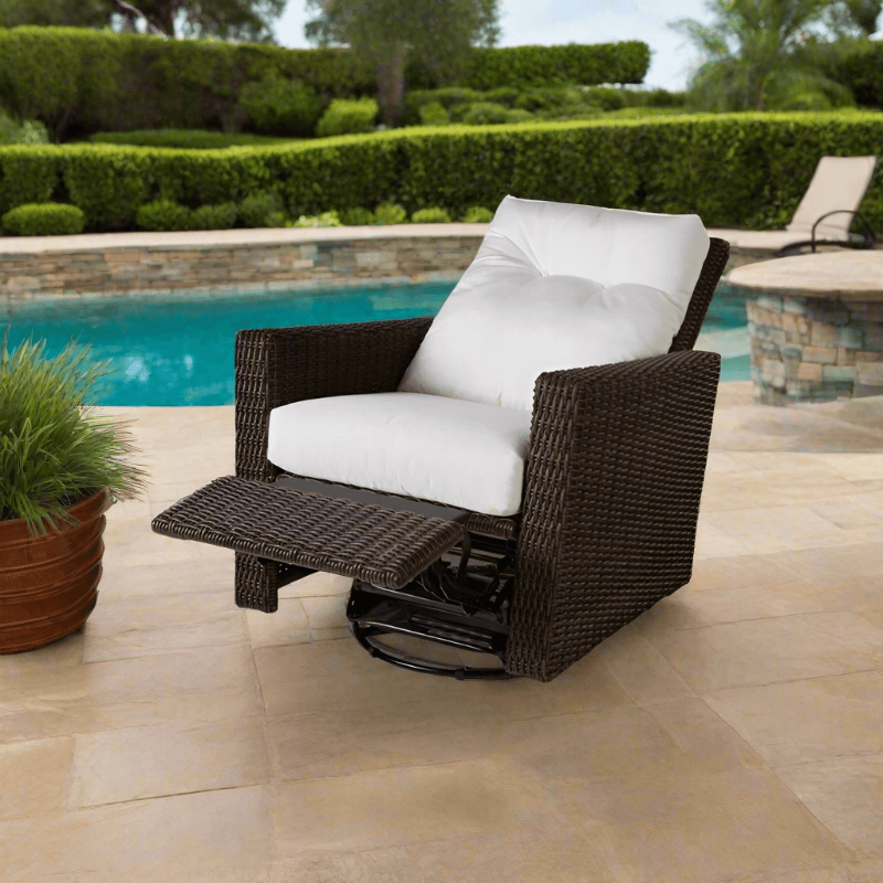 Brown wicker chair with white cushion on a patio by a pool