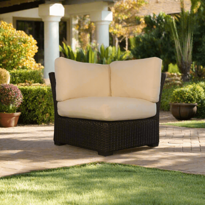 Wicker outdoor loveseat with beige cushions on a patio
