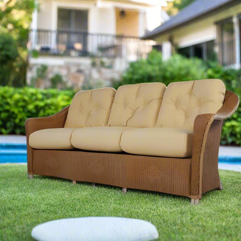 Beige sofa with wicker frame in a room with large windows and plants
