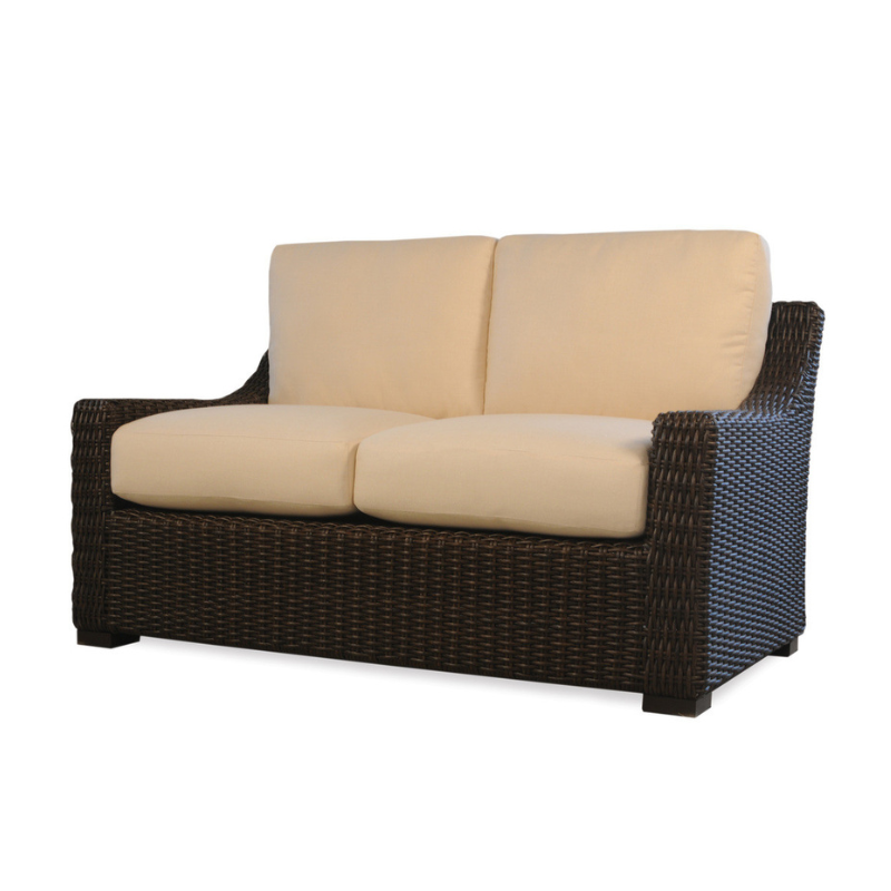 Wicker loveseat with beige cushions on a white background