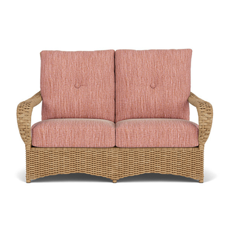 Wicker loveseat with pink cushions on a white background