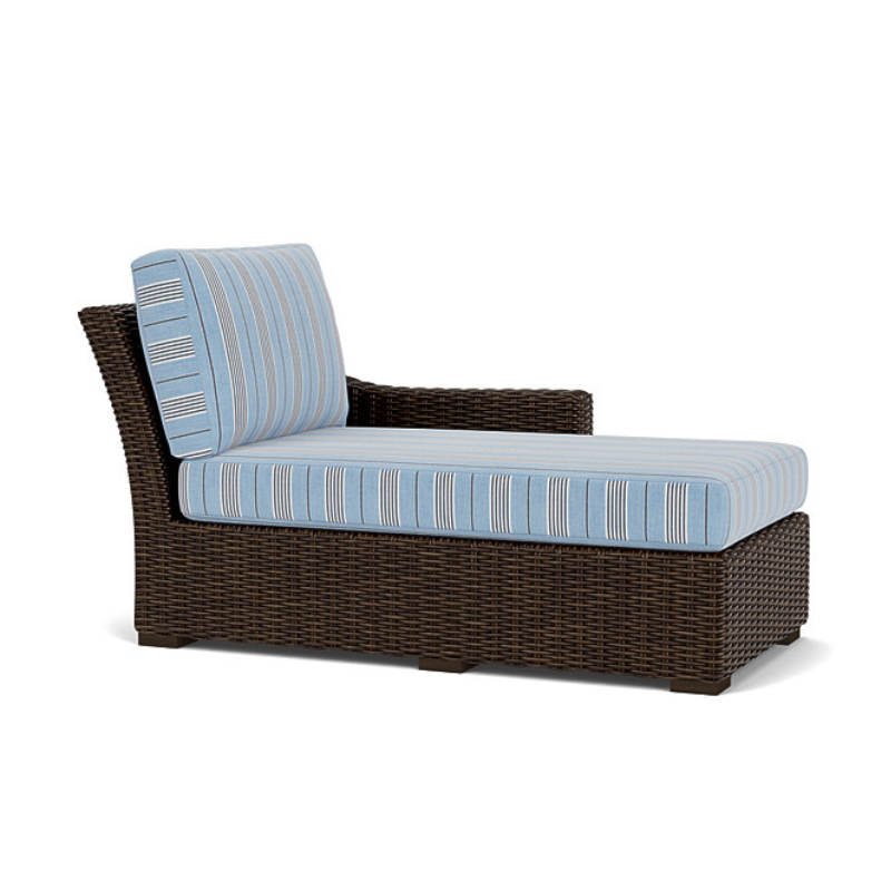 Wicker outdoor lounge chair with blue cushions on a white background