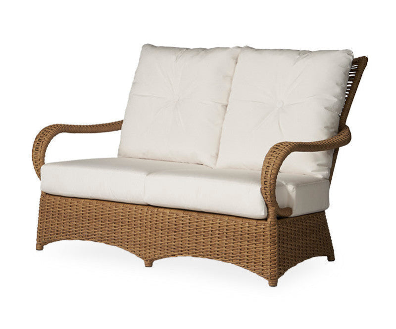 Wicker loveseat with white cushions on a white background