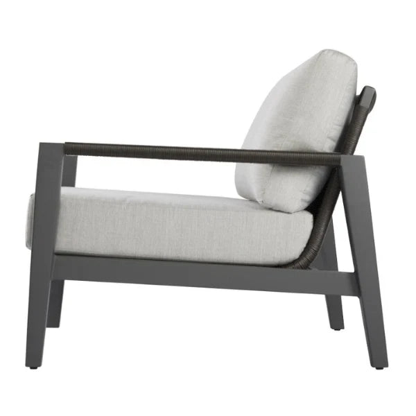 A modern outdoor lounge chair with a dark gray frame, woven armrests, and light gray cushions, shown from a side profile view on a white background.