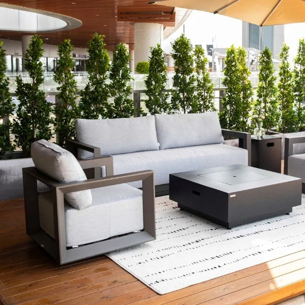 Outdoor patio furniture set with gray cushions and a fire pit table on a wooden deck.