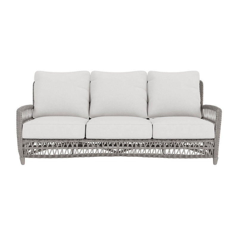Gray wicker outdoor sofa with white cushions on a white background