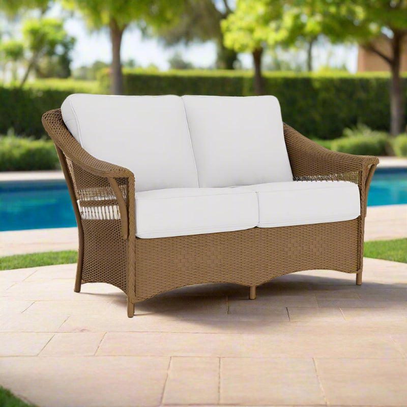 Brown wicker outdoor sofa with white cushions on a white background