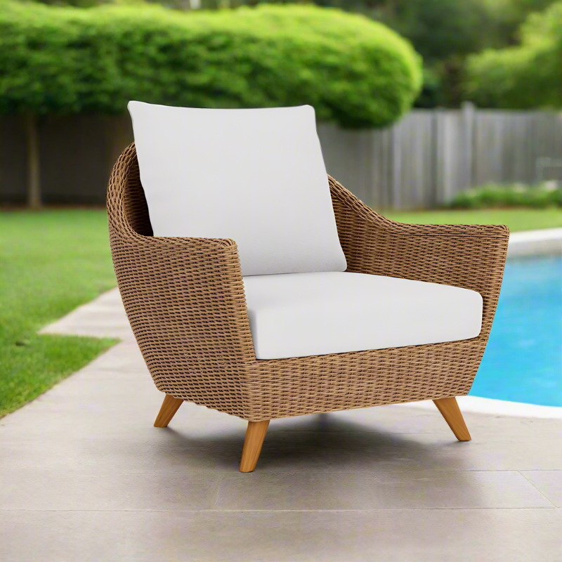 Wicker armchair with white cushions by a poolside