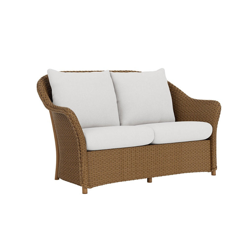 Brown wicker loveseat with white cushions on a white background
