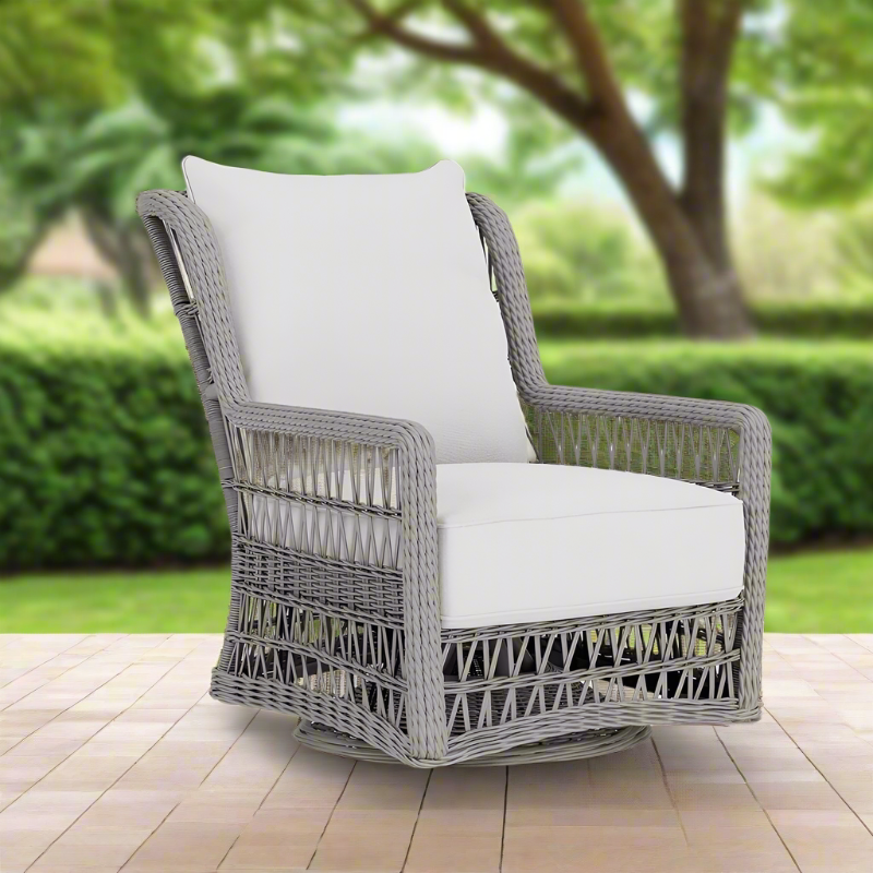 Gray wicker chair with white cushion on a wooden deck with greenery in the background