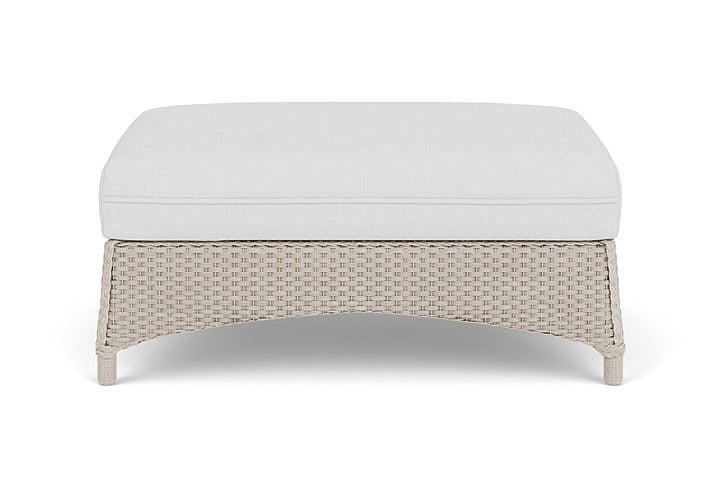 Wicker ottoman with white cushion on a white background