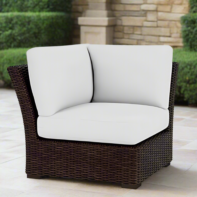 Wicker outdoor chair with white cushions on a patio