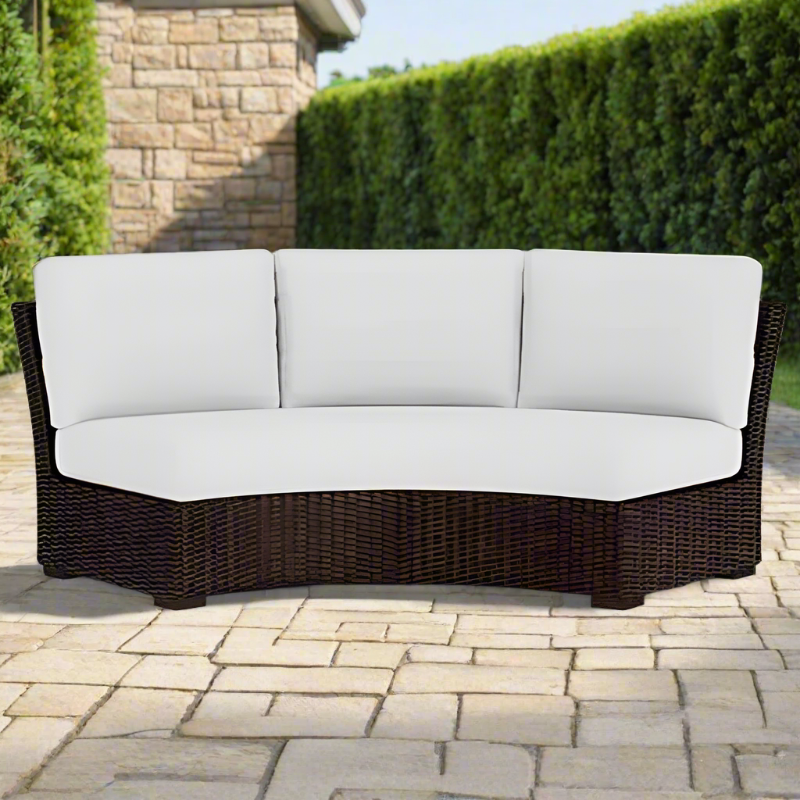 Wicker outdoor sofa with white cushions on a patio