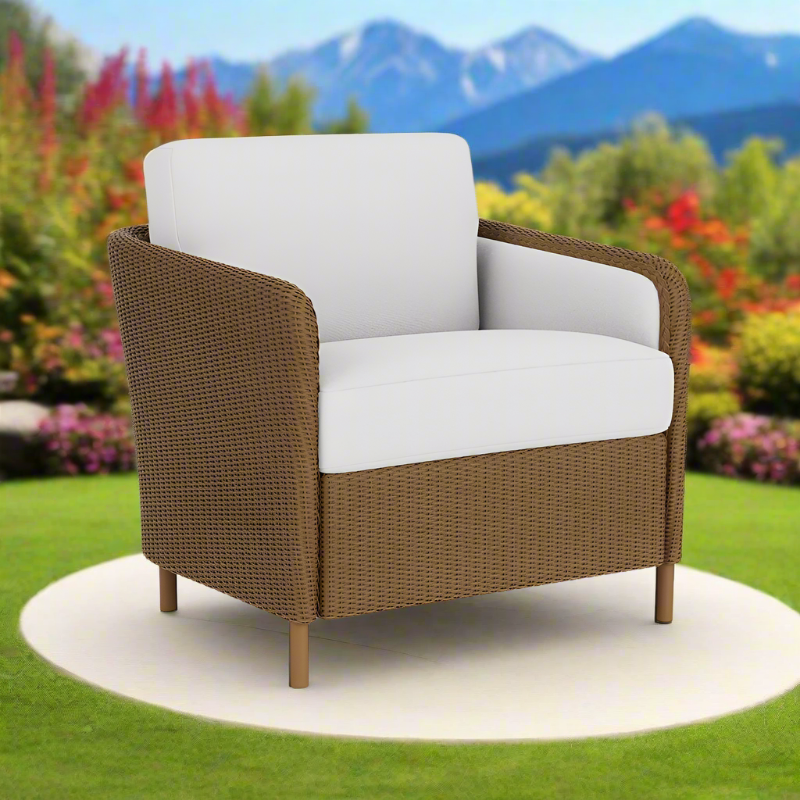 Brown wicker chair with white cushions in a garden setting with mountains in the background