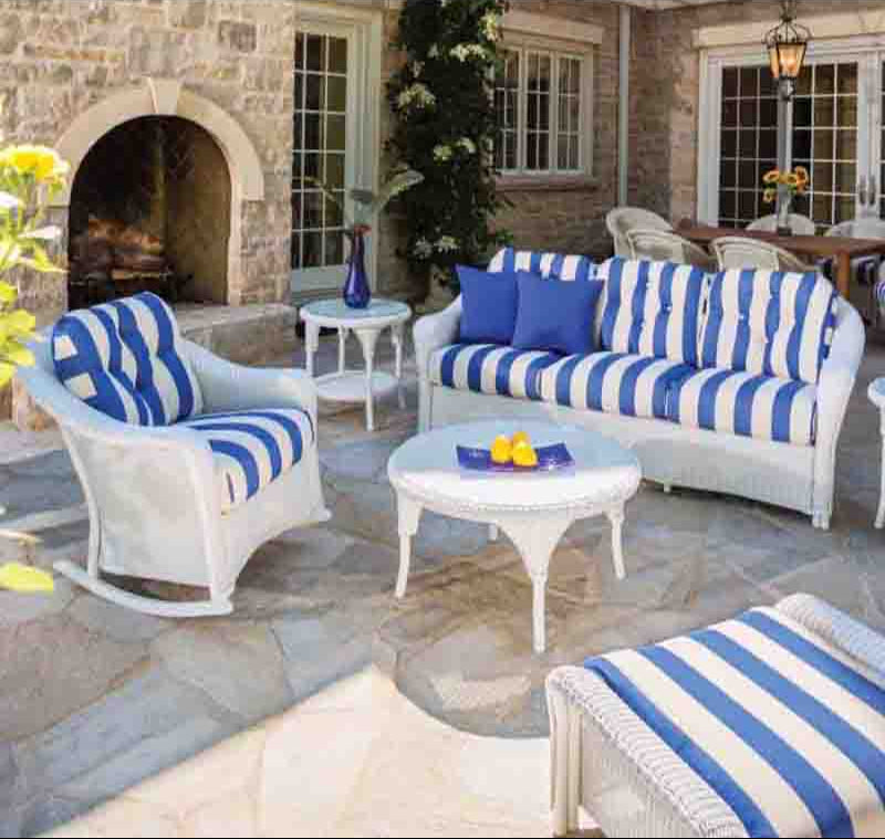 Outdoor patio set with blue and white striped cushions on a stone patio.