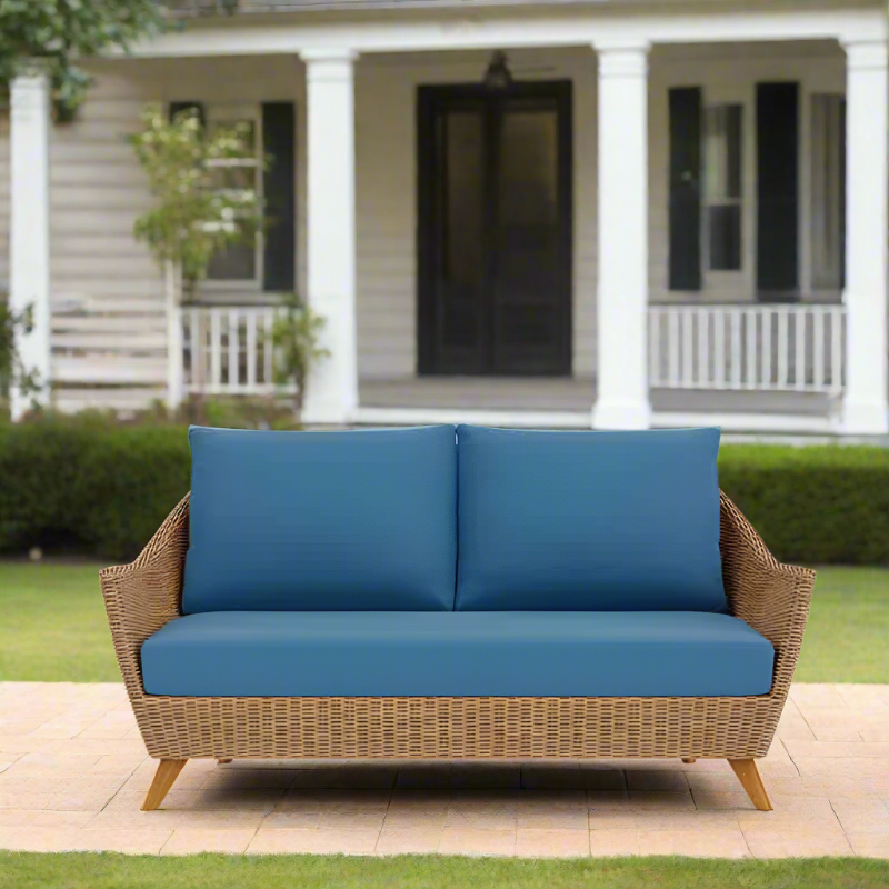 Outdoor wicker sofa with blue cushions in front of a house.
