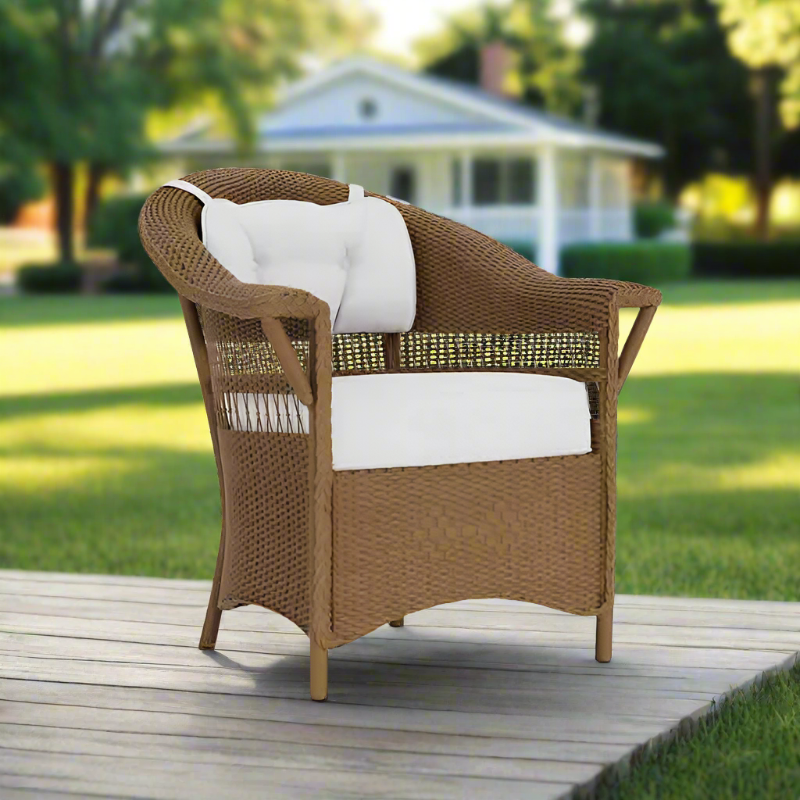 Wicker chair with white cushions on a wooden deck in a garden setting