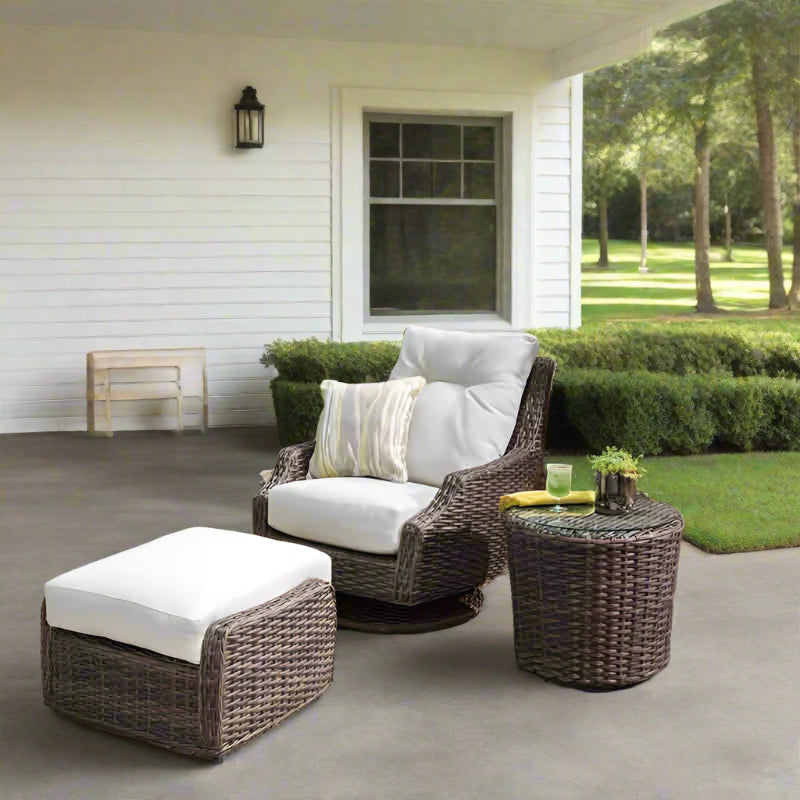 Outdoor patio set with wicker chairs and ottoman on a stone patio with garden background
