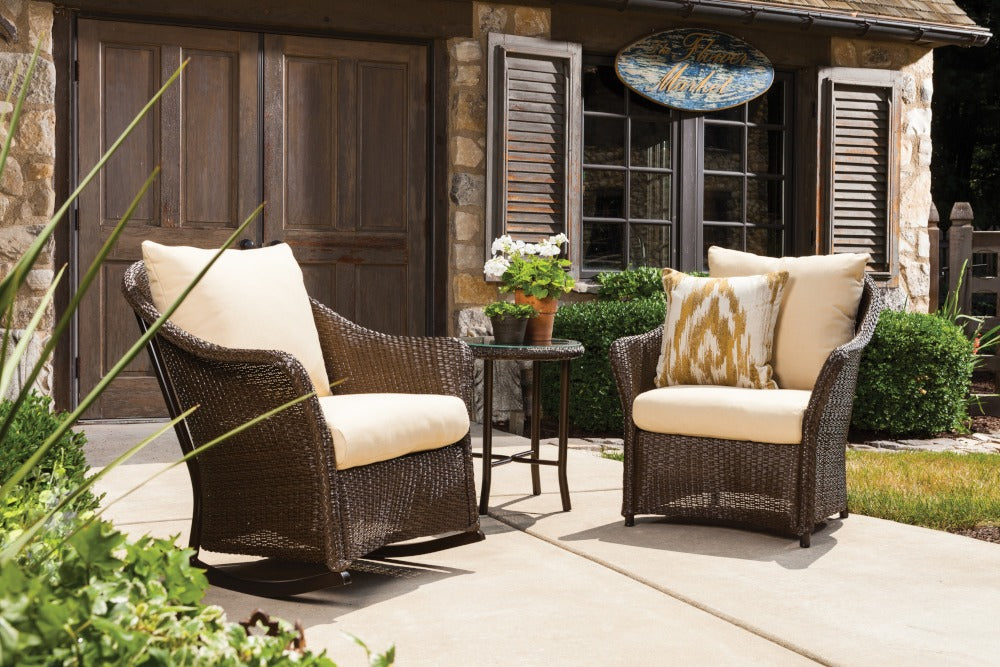 Outdoor patio furniture set with wicker chairs and cushions on a patio.