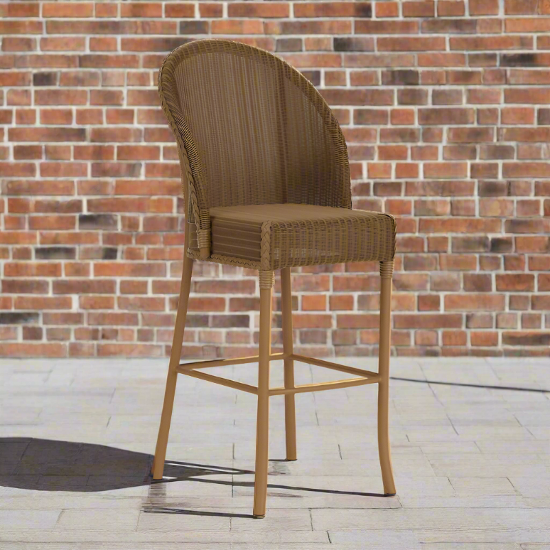 Brown wicker bar stool against a brick wall.
