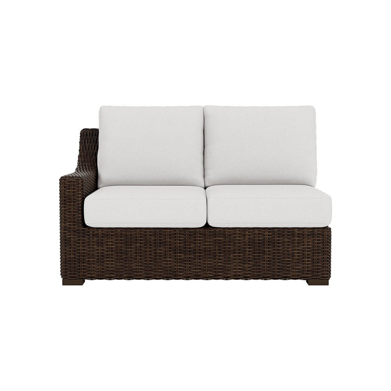 Wicker outdoor sofa with white cushions on a white background