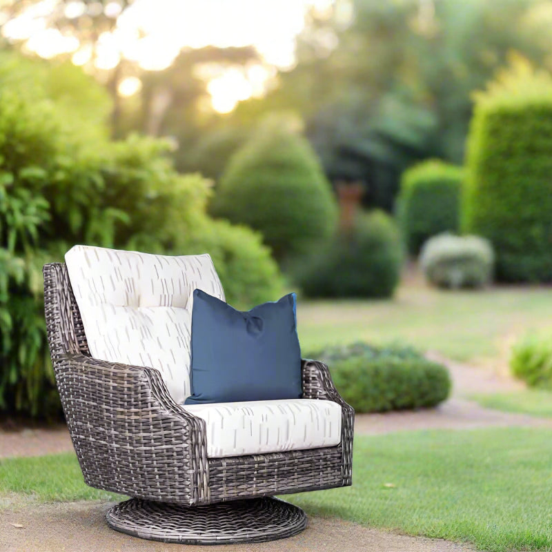 Wicker chair with white cushion and blue pillow in a garden setting